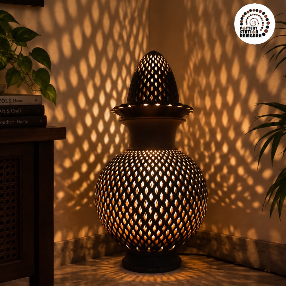 The Lota Lamp lit from within, with a Pottery Station logo mark in the corner.